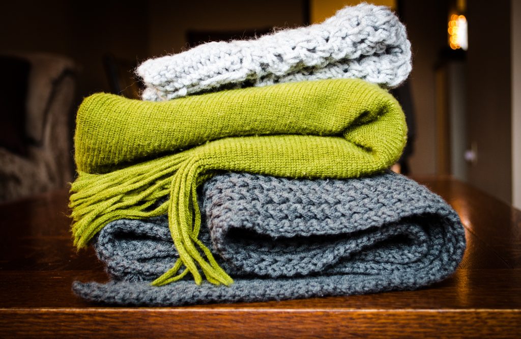 light grey, lime green and dark grey knitwear folded on top of one another