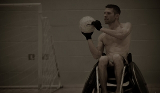Naked man in wheelchair playing basketball