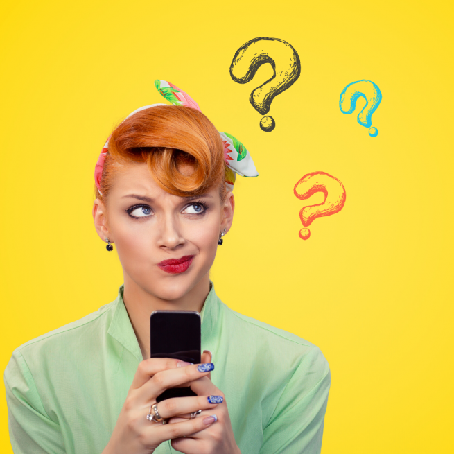 A girl stands in front of a yellow background. She has orange hair styled in a retro fashion with a headscarf and a pale green shirt. She is holding her phone in front of her and is looking off to her left with a thoughtful expression on her face. there are cartoon question marks to the side.