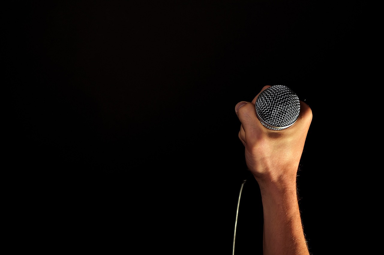 A man's hand holding a microphone with a black background