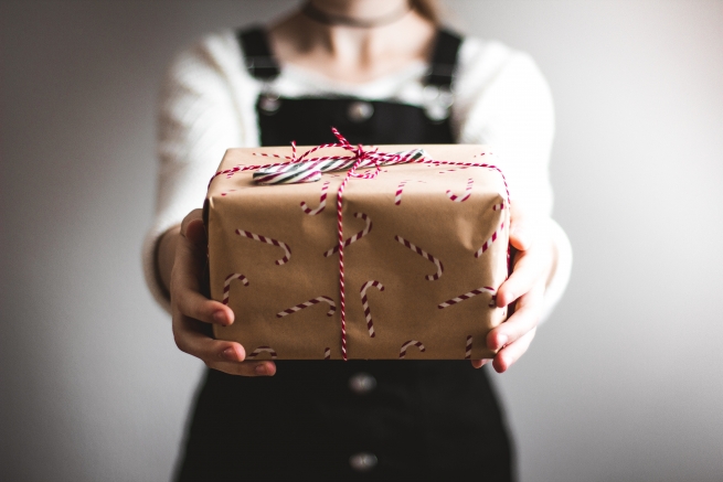 a girl holding a christmas present wrapped in brown paper