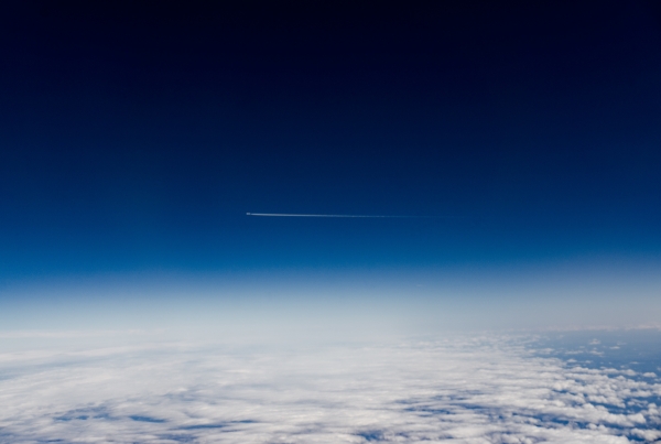 The earth and clouds below, a plane cruising at high altitude and above, space