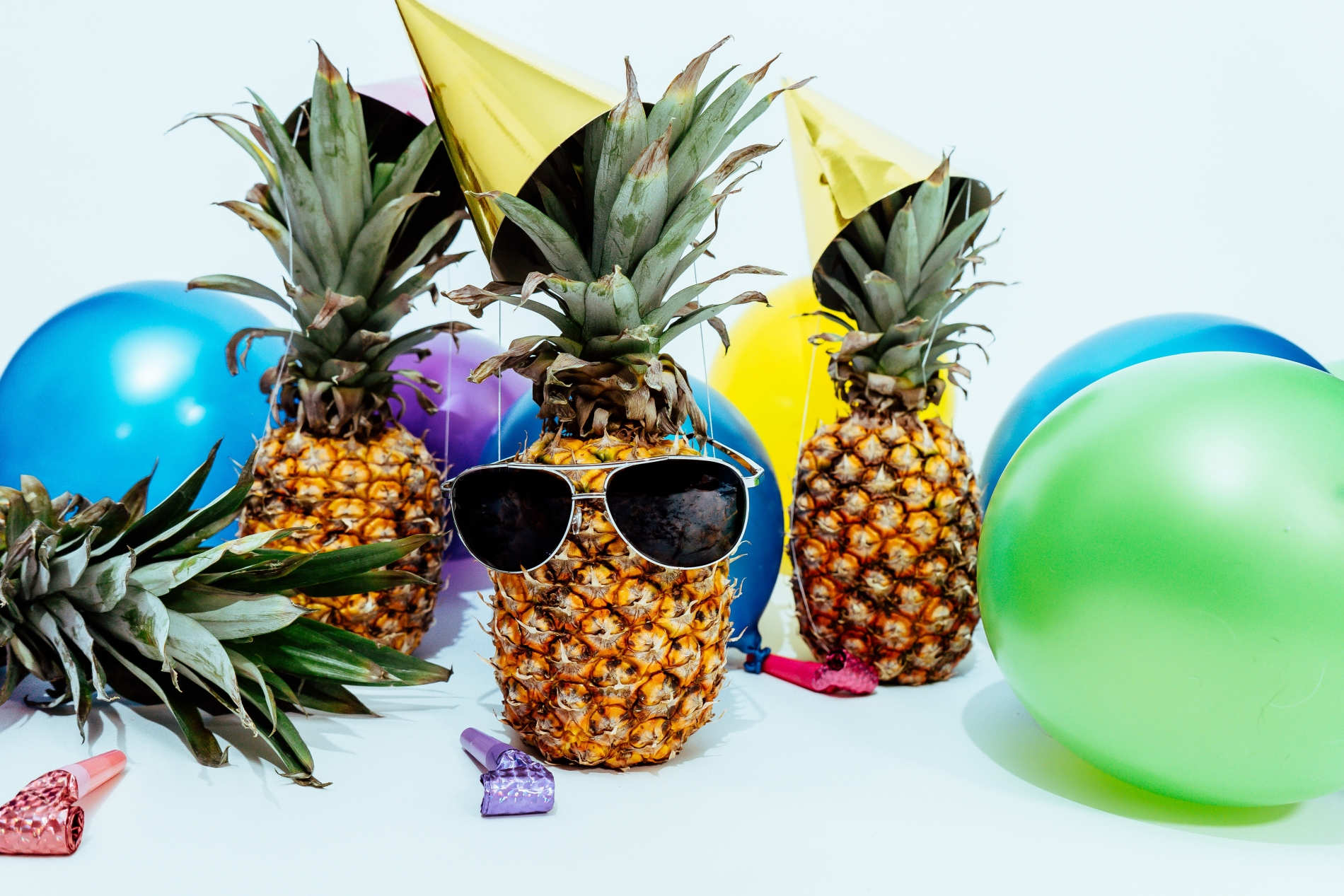 pinapples party hats, balloons and party poppers