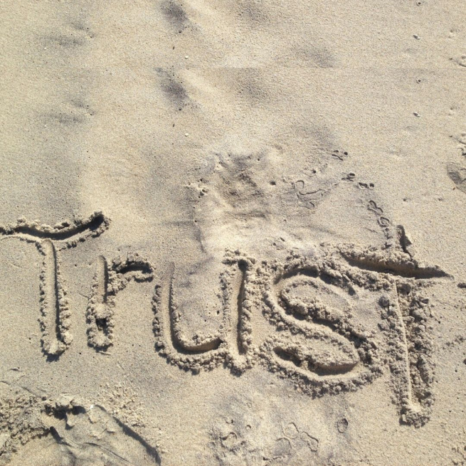 The word Trust written in the sand