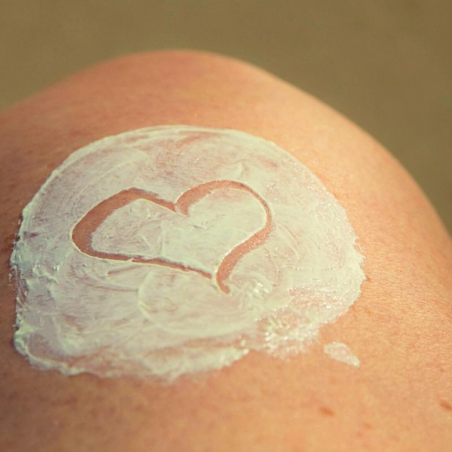 Body lotion spread on pale skin with a love heart drawn in the lotion
