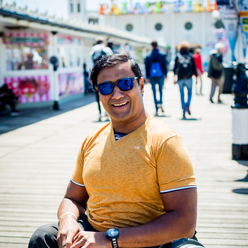 Jig sat in his wheelchair smiling on Brighton Pier