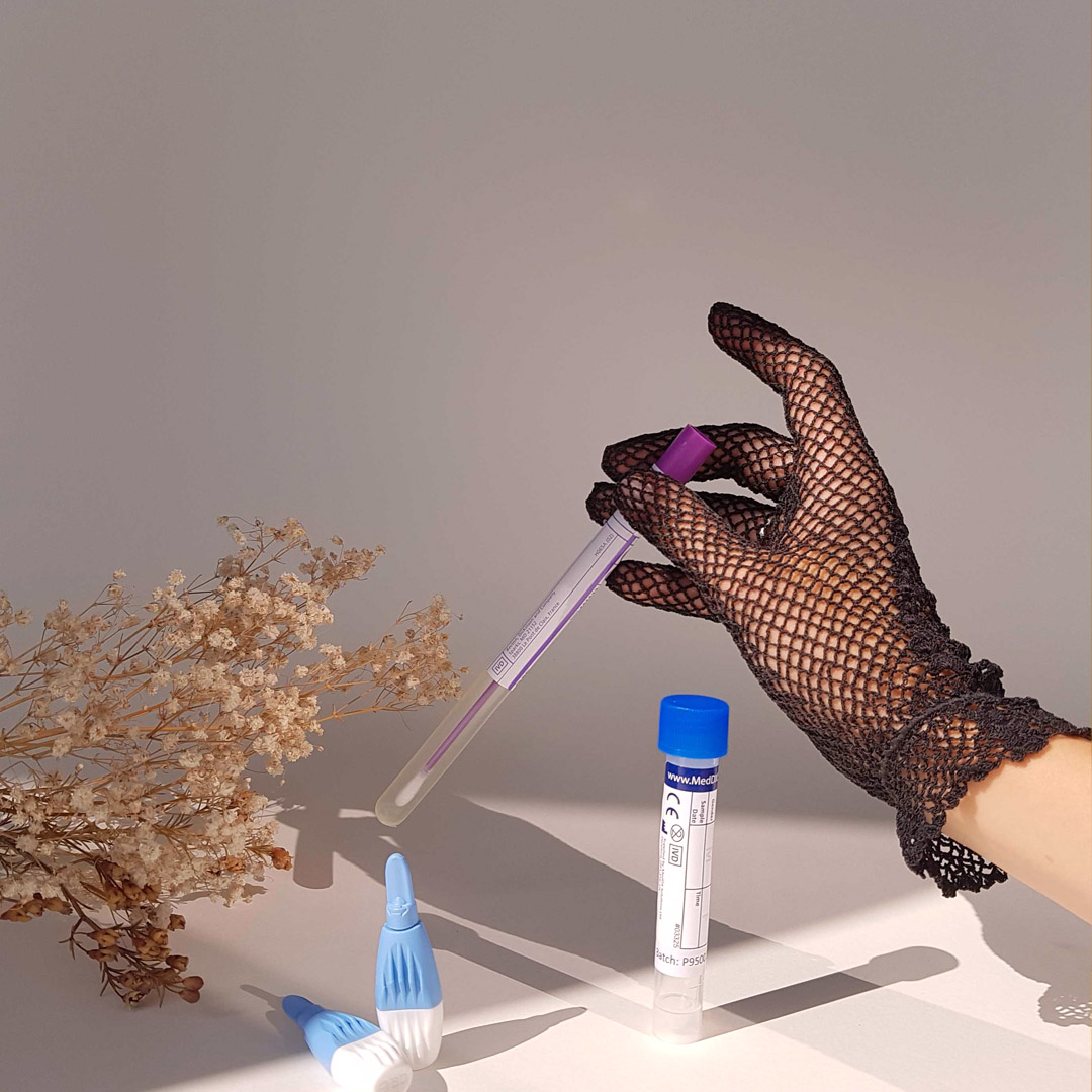 STI tests and a hand in a black lace glove holding one.