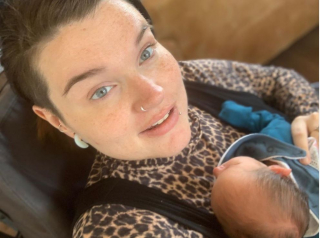 Kelly holds her newborn son Hunter, she is wearing a leopard print top and has dark hair and blue eyes