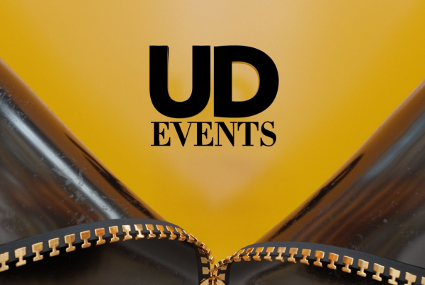 A leather jacket unzipped to reveal a yellowy orange background with the words UD events in black
