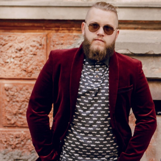 Styling It Out and Sweaty Pits - a trendy young guy wears a burgundy velvet suit jacket with a patterned T-shirt underneath. He has a hipster beard, a man bun and sunglasses