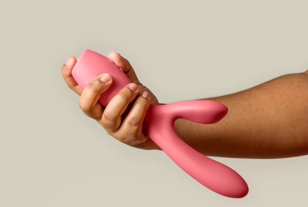 Someone holding a pink vibrator. It is larger than their hand