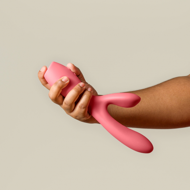 Someone holding a pink vibrator. It is larger than their hand