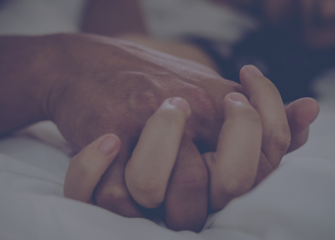 Male and female hands intertwined on a bed