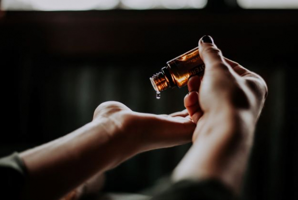 A photograph of someone dropping massage oils on their hands