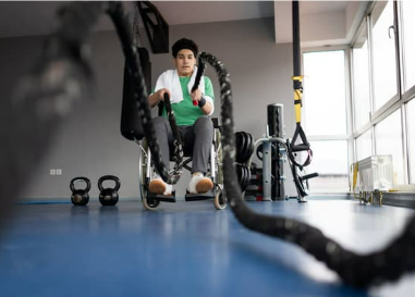 Image of a wheelchair user in a gym, working out using ropes