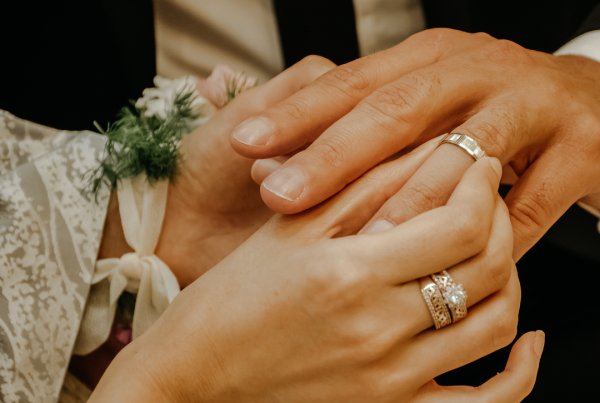 close up photograph of two people putting their wedding rings on each other hands
