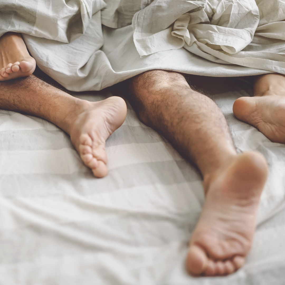 Photo of two peoples feet sticking out at the end of the bed.