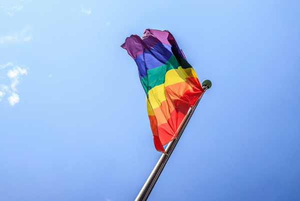 Disability Pride Month: A rainbow flag floating in the air against a clear blue sky