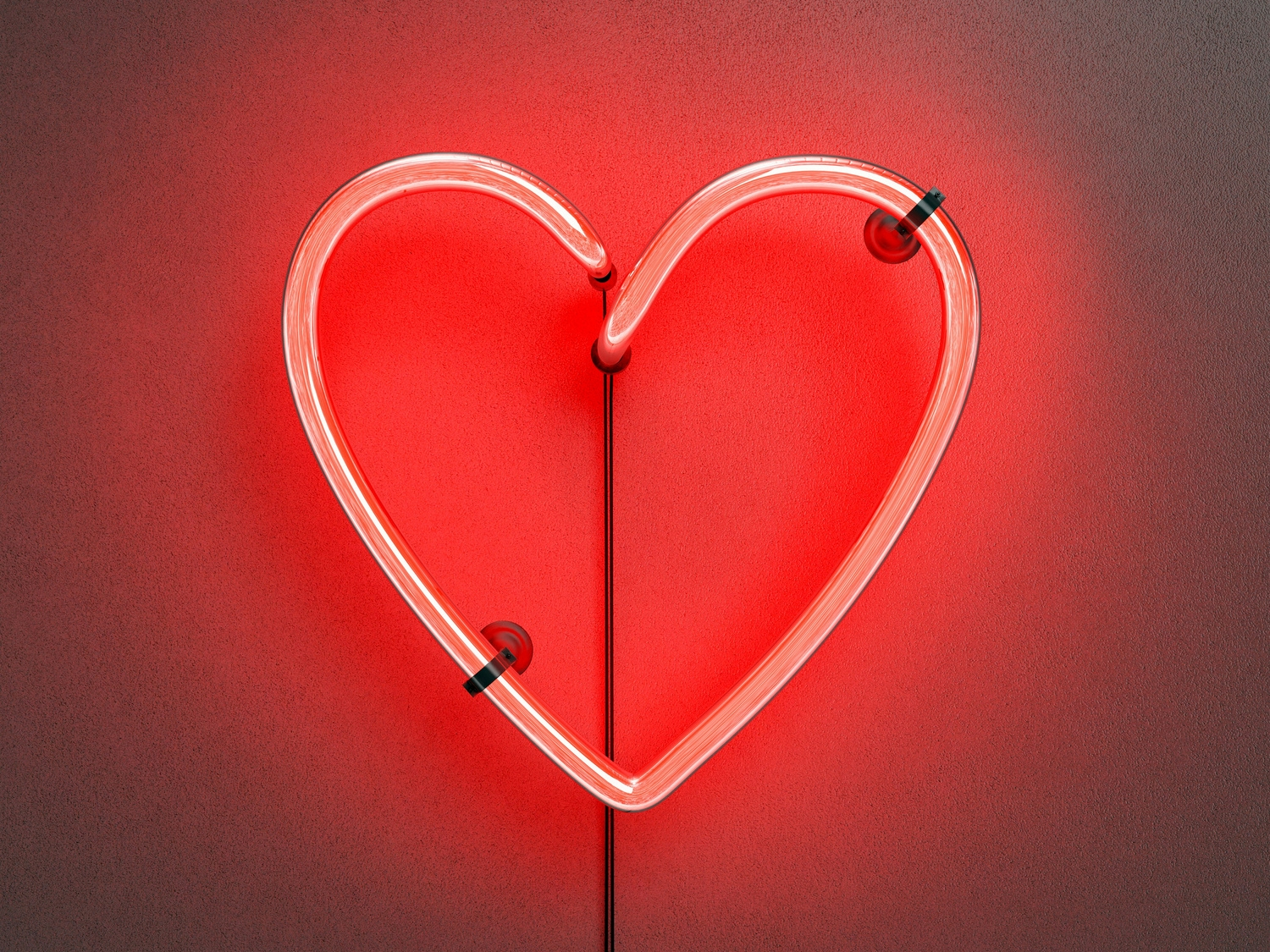 A glowing neon heart sign in red against a dark background.