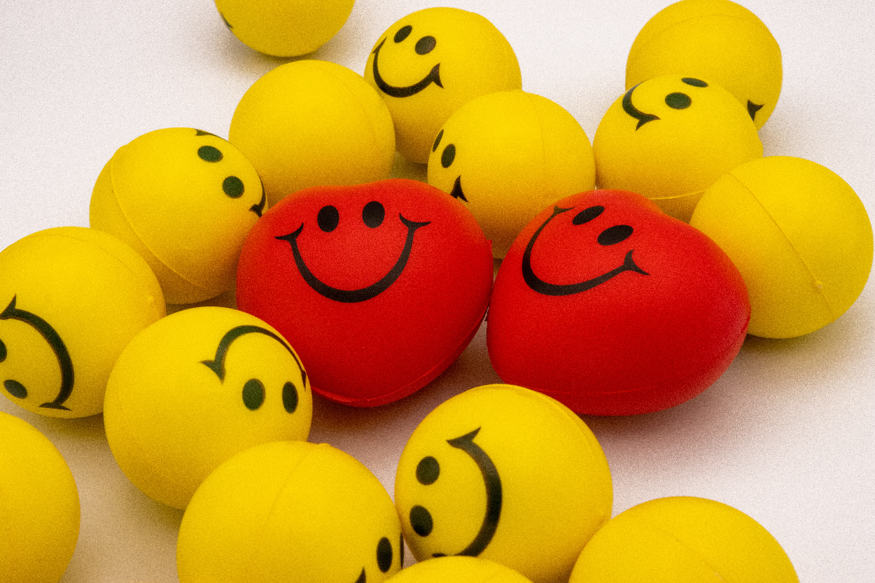 A pile of smiley faces. They are round and yellow, and heart-shaped and red.