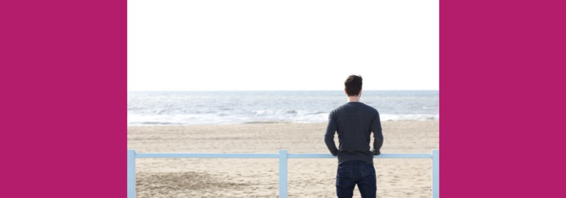 A man looking out to sea on the beach.