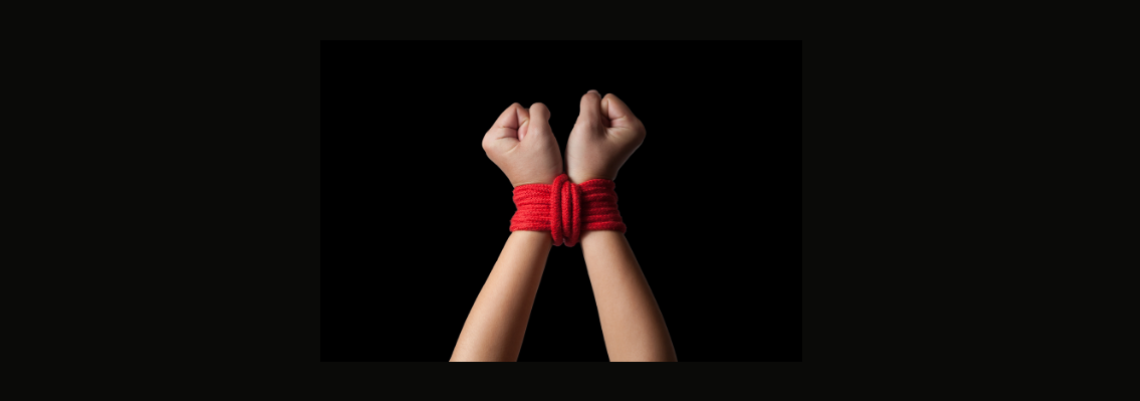 Hands intricately bound with red rope.