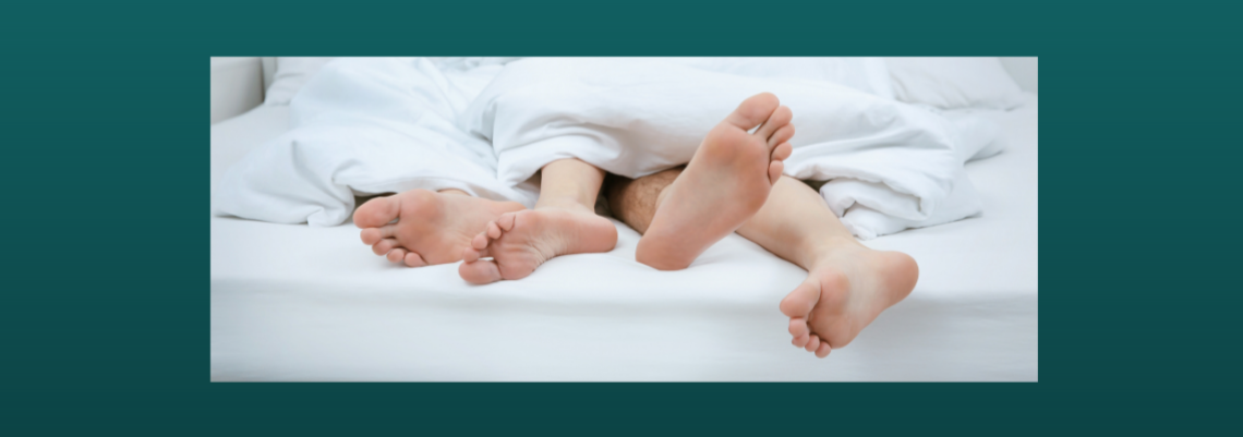 Two pairs of feet poking out from under bedsheets.