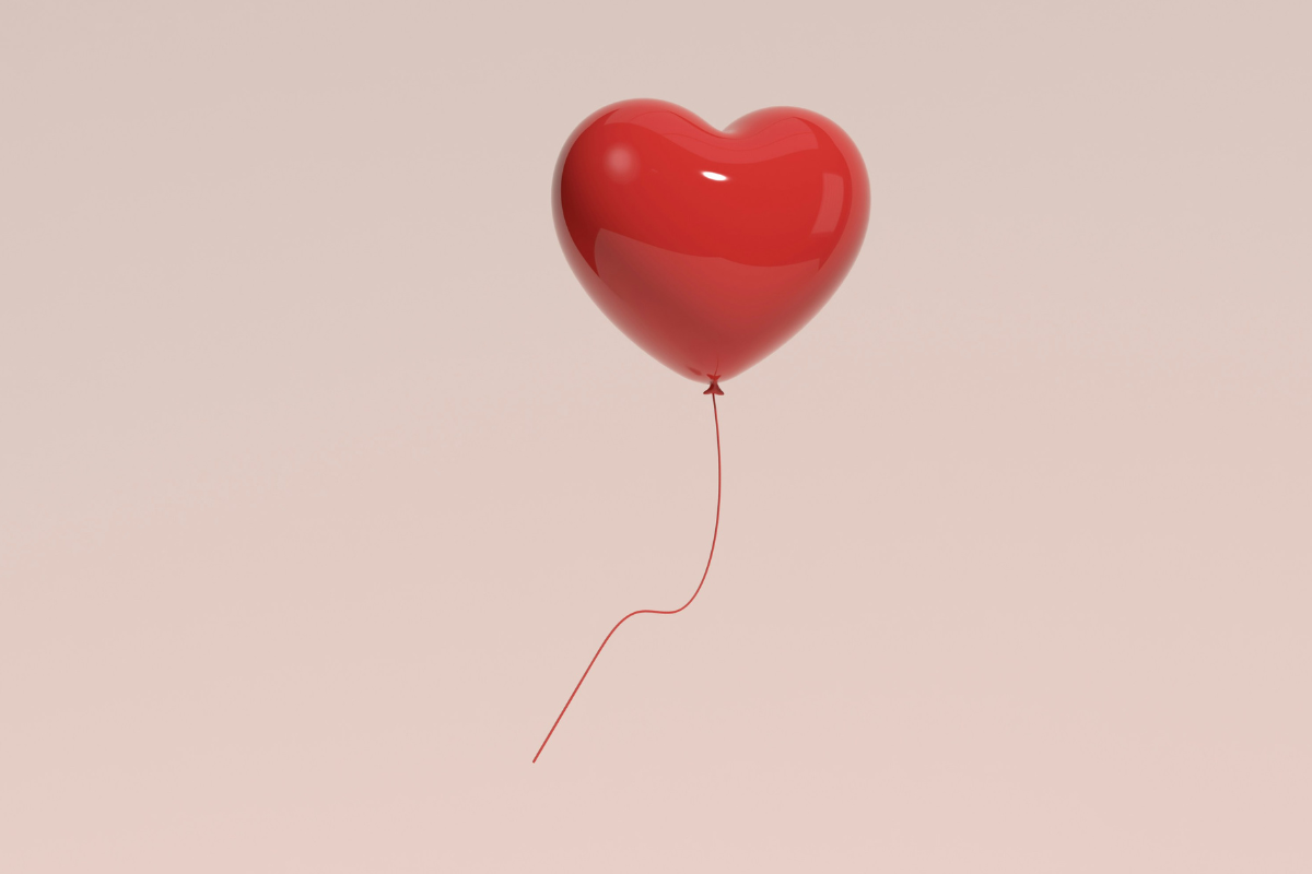 Menopause event: A red heart shaped balloon floating against a pink wall