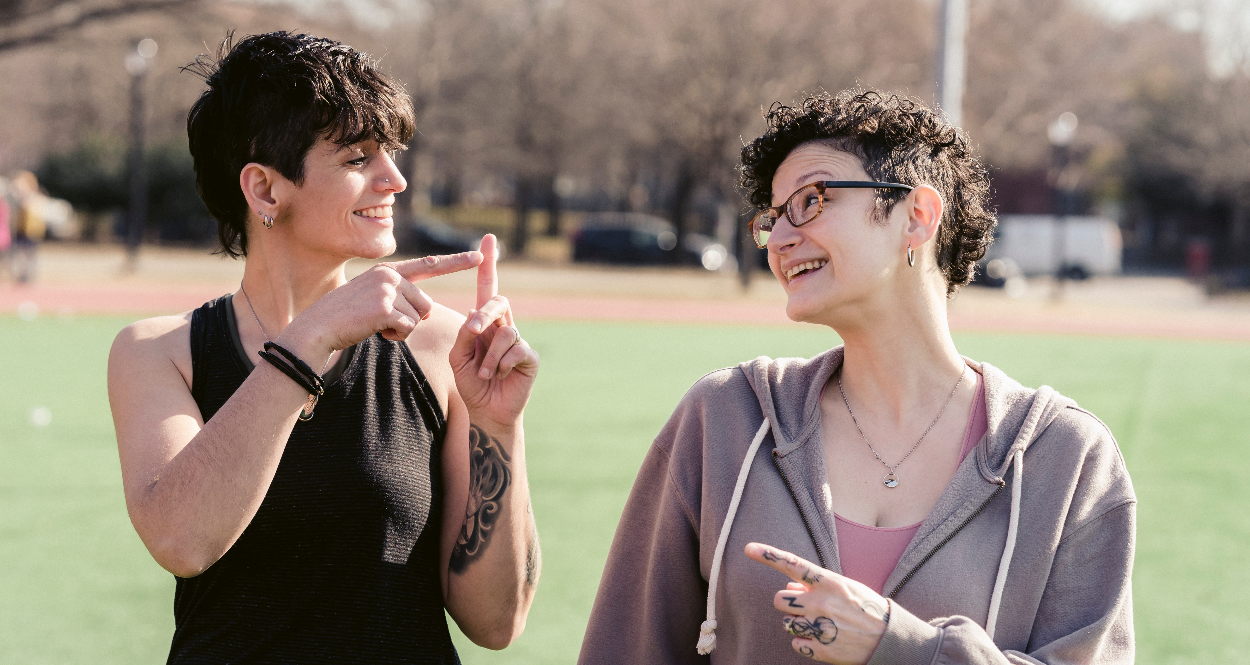 Two people standing in a field communicating with sign language.