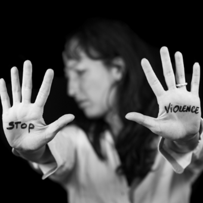 A woman holds her hands out and is looking away from the camera. On each hand is a word - "Stop violence"