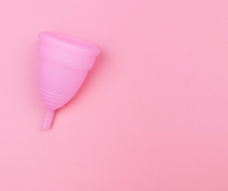 Periods: A pink moon cup lying on its side against a pink backdrop