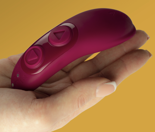 A pink vibrator remote sitting in the palm of someone's hand.