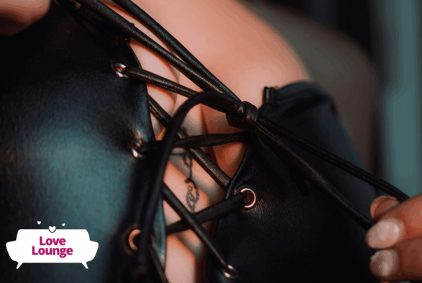 A person is pulling the strings of a black PVC top closed over their breasts