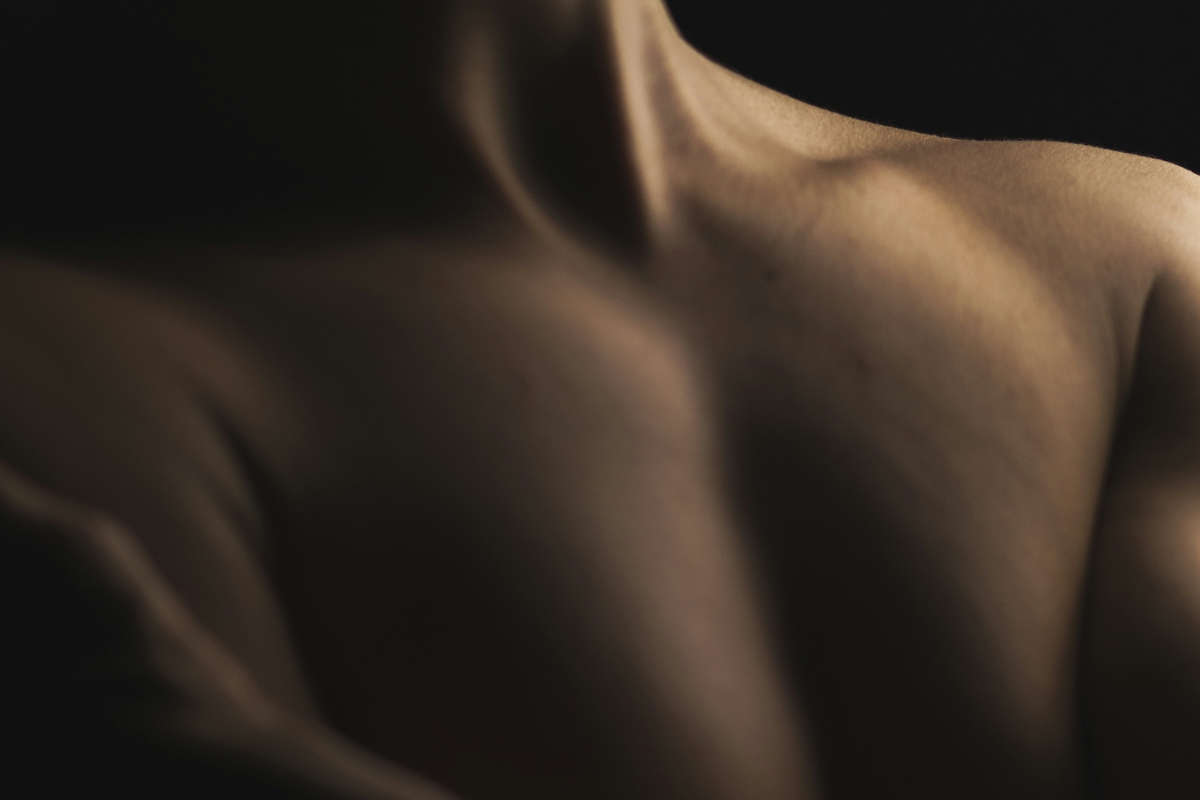 The neck and shoulders of a person. A close up in low light